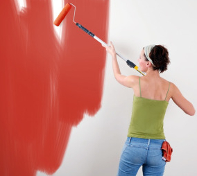 A woman painting over wallpaper