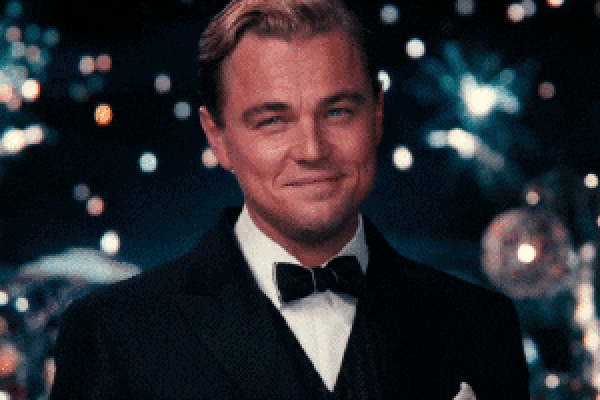 Leonardo DiCaprio in a tuxedo smiling and raising a glass toward the viewer