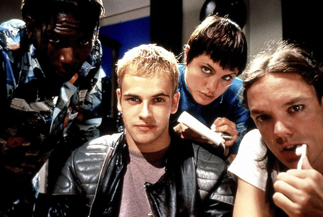 Four characters gathered around a computer from a scene in the film Hackers
